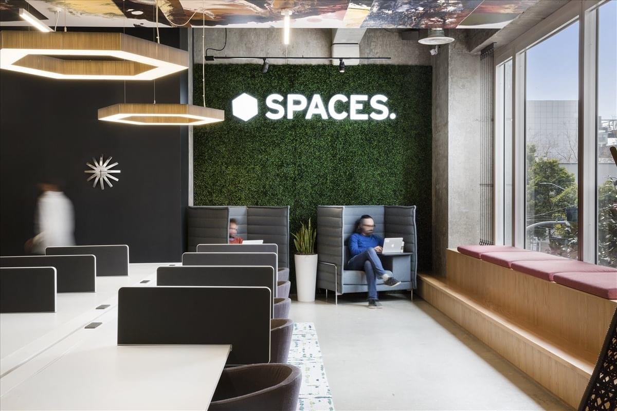 Modern coworking area at The Paramount Building featuring a lush green moss wall and integrated booth seating.