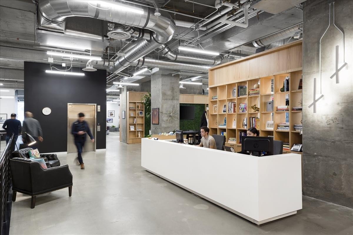 Lobby area at The Paramount Building showing a long white reception desk and industrial ceilings.
