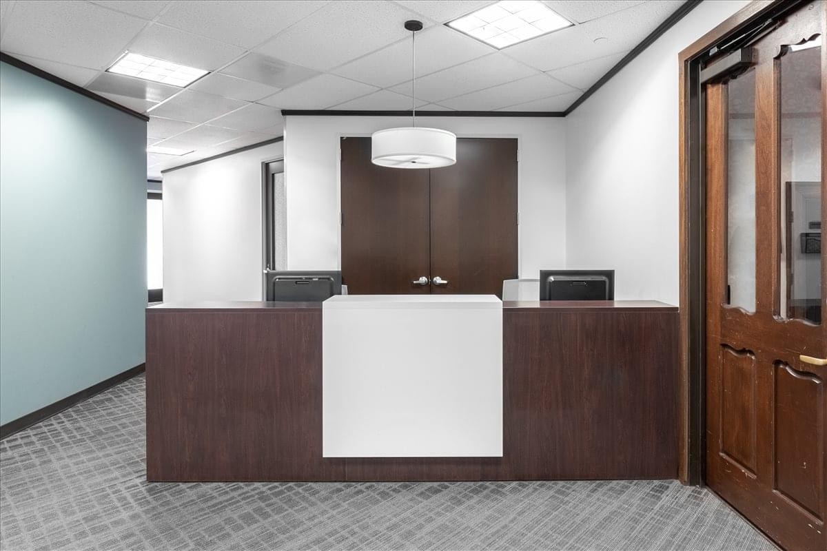 Professional reception area of 9501 Echo Lane, Suite 200, Memorial with a modern dark wood front desk.