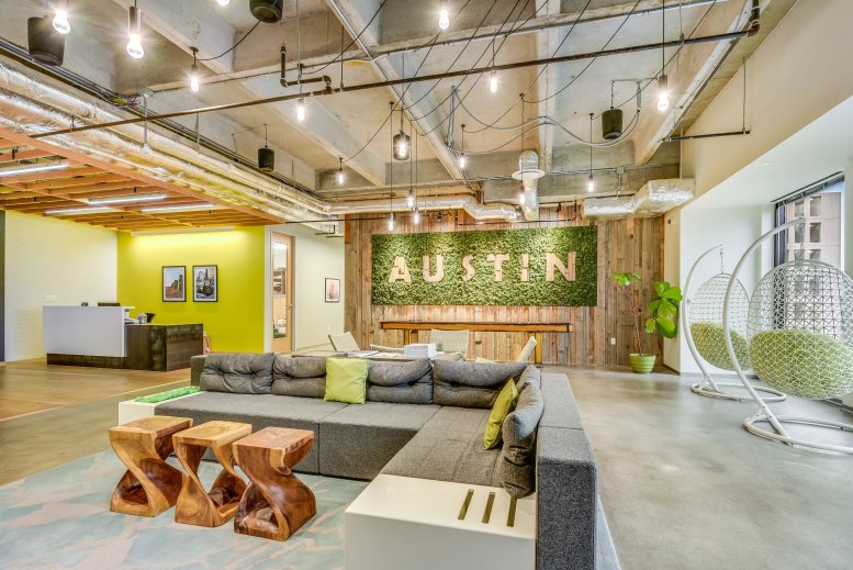 Spacious reception and lounge at 98 San Jacinto with a moss wall and modern wooden seating.