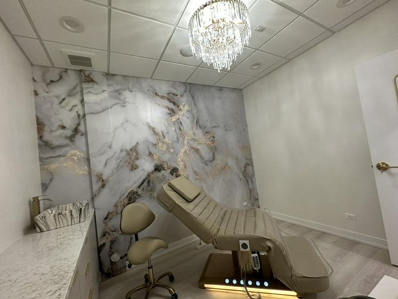 Treatment room at Beauty Empire Suites with a marble-patterned feature wall and a modern spa chair.