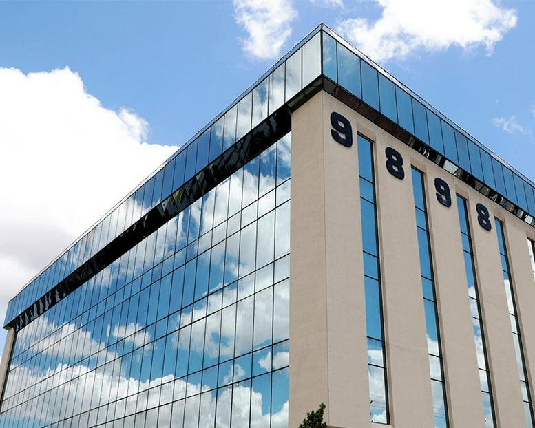 Modern exterior view of 9898 Bissonnet Street against a bright blue sky with white clouds.