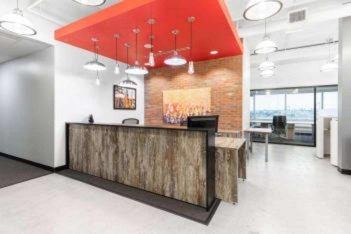 Reception desk at 99 Wyse Road, Suite 1100 with wood paneling and a vibrant red ceiling feature.