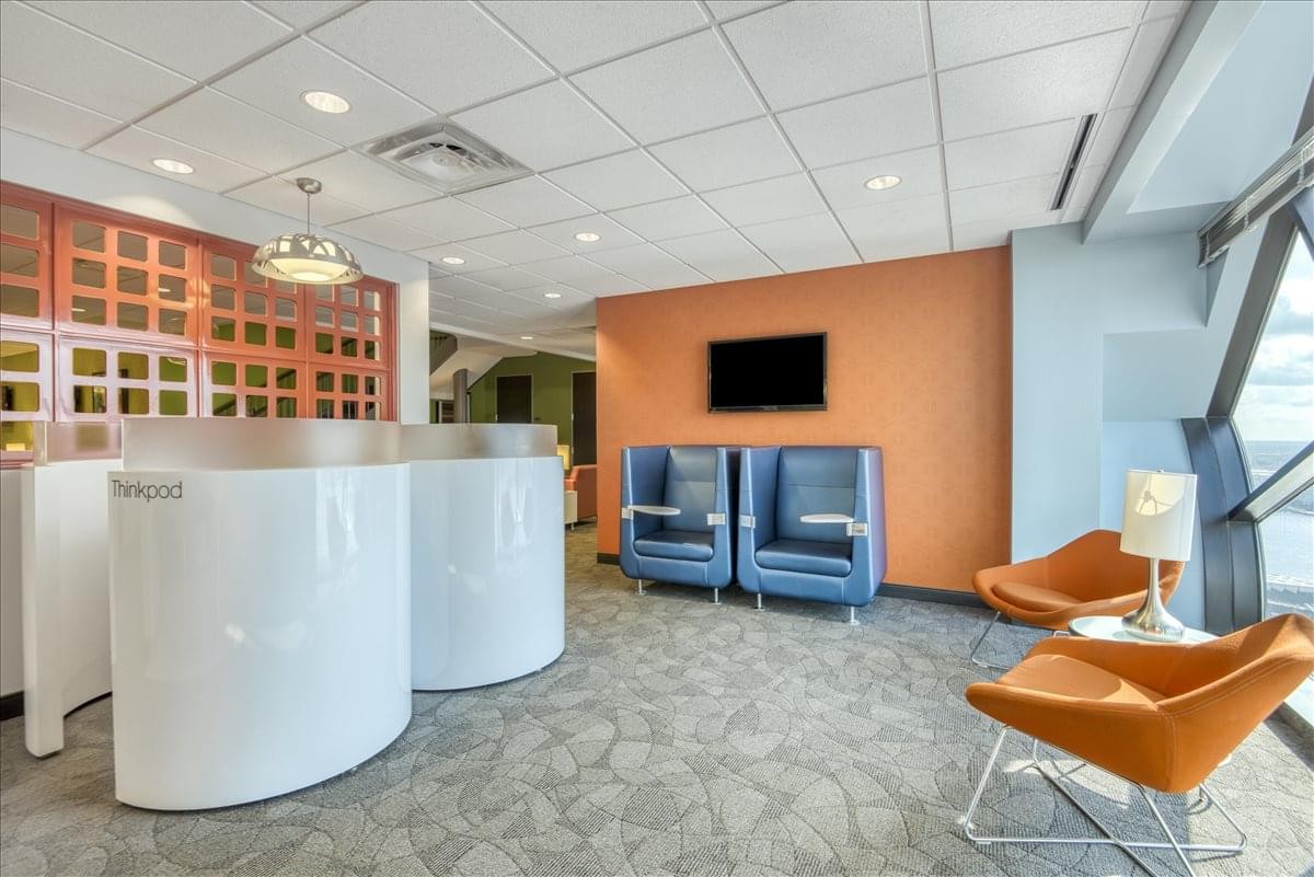 Reception waiting area at 999 Waterside Drive, Suite 515 with orange accent walls and stylish lounge seating.