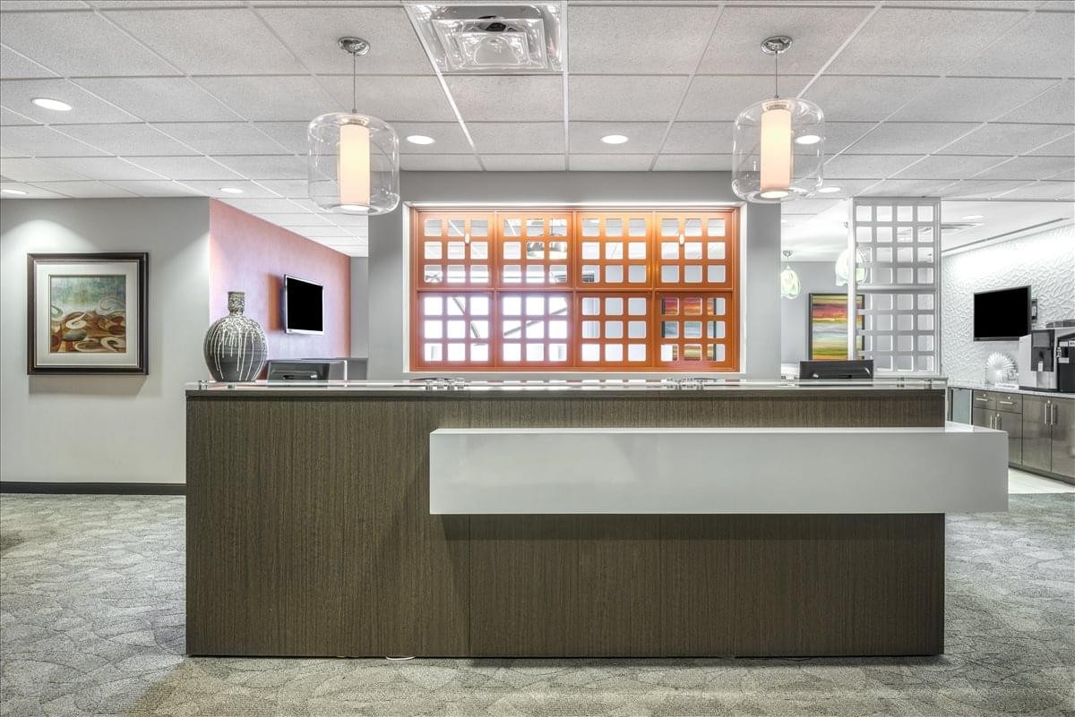 Modern reception desk at 999 Waterside Drive, Suite 515 with sleek pendant lighting and wood paneling.