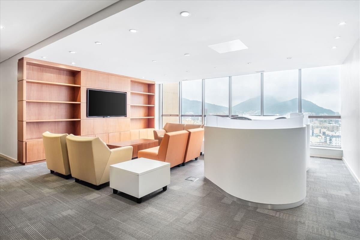 Bright lounge area with comfortable armchairs, a curved white reception desk, and mountain views.