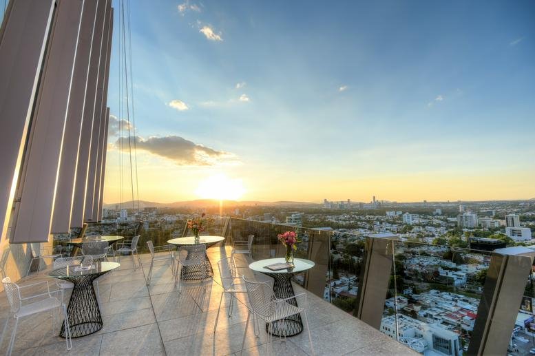 Spacious rooftop terrace with lounge tables at sunset overlooking the city.