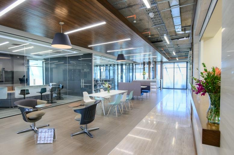 Wide view of a modern open-plan office with high ceilings, wooden accents, and diverse seating.