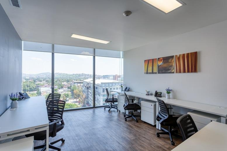 Shared office space at Av. Baja California 274 featuring white desks and large windows.