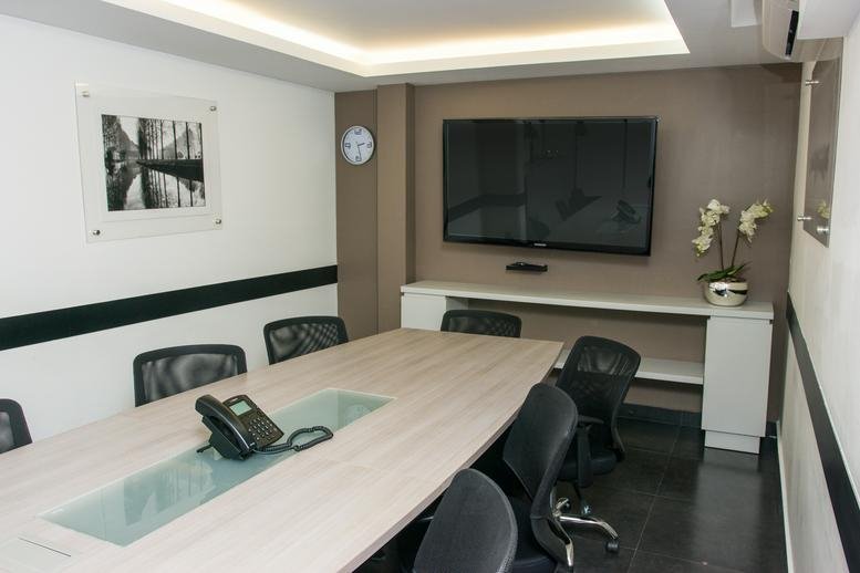 Professional meeting room featuring a long conference table, wall-mounted TV, and recessed lighting.