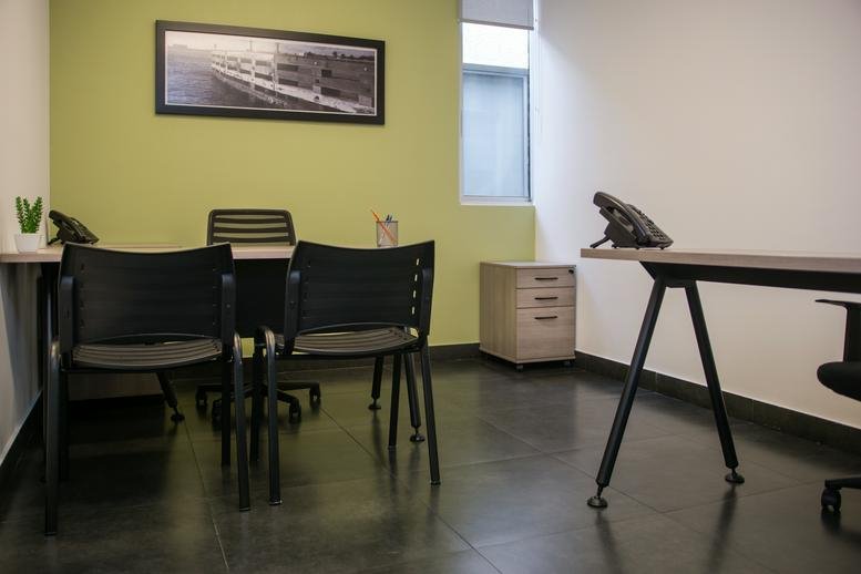 Internal office suite with two separate desks and light green accent wall.