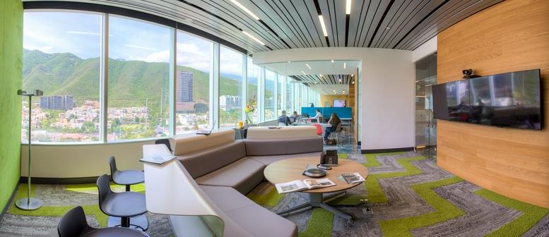 Spacious communal lounge with a large sectional sofa, green accents, and mountain views.