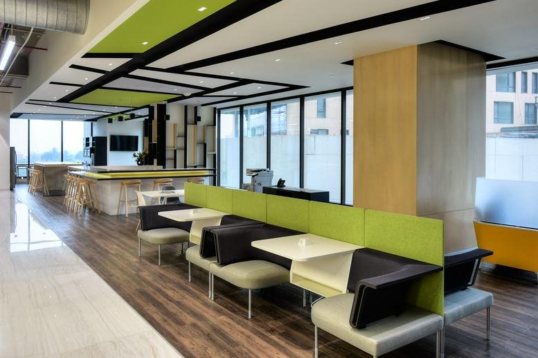 Bright coworking lounge with lime green dividers and comfortable booth seating.