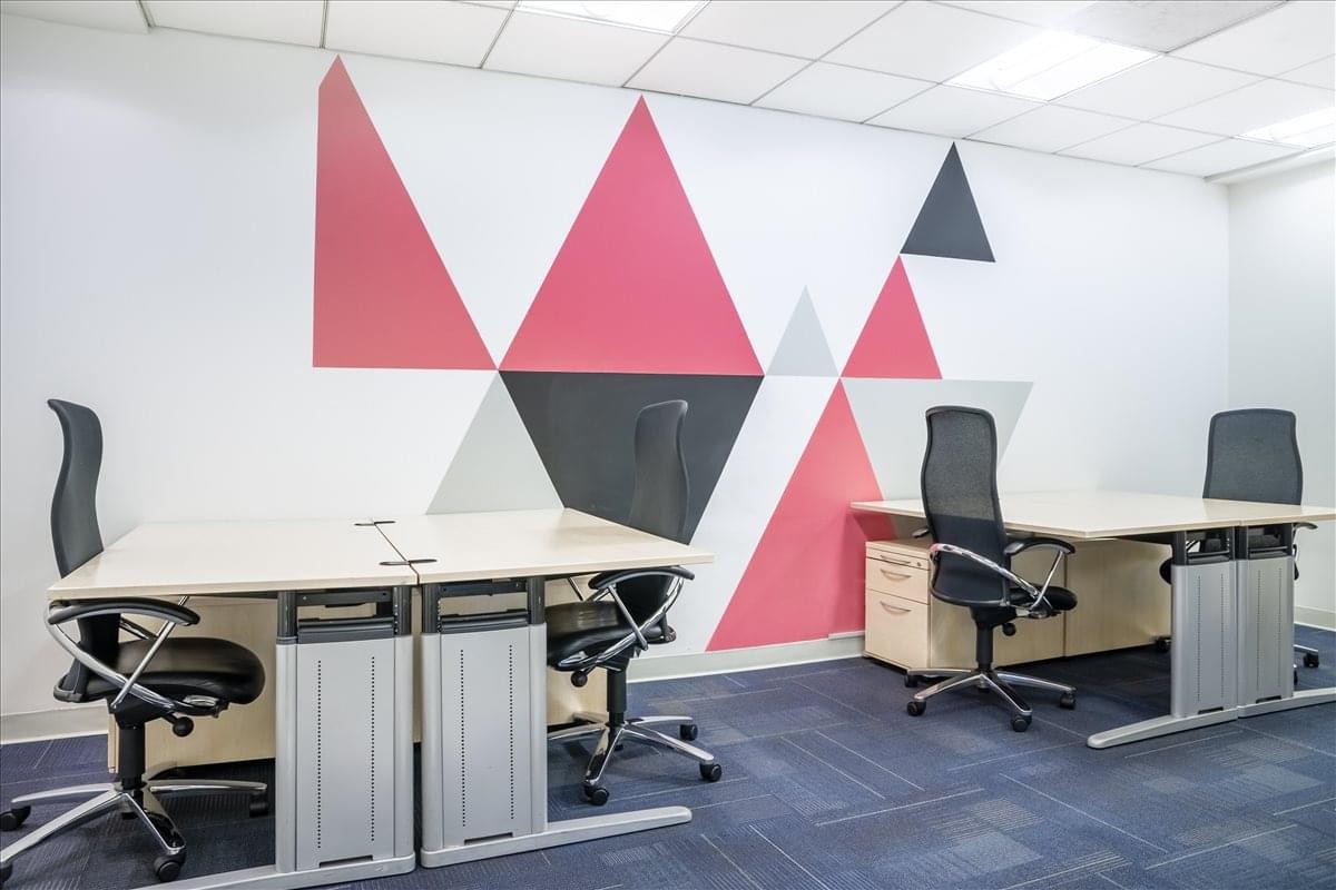 Bright office space featuring a vibrant red and grey geometric accent wall.