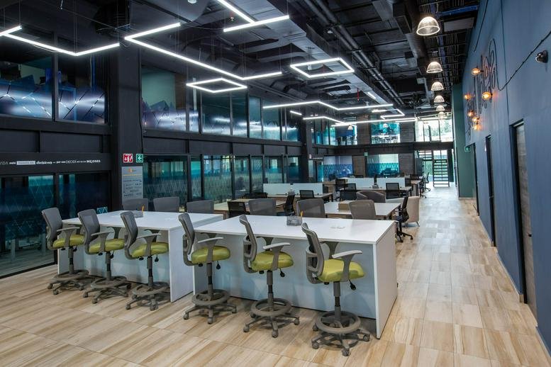 Modern coworking area at Av. Insurgentes Sur No. 105 with stylish lighting and long white desks.