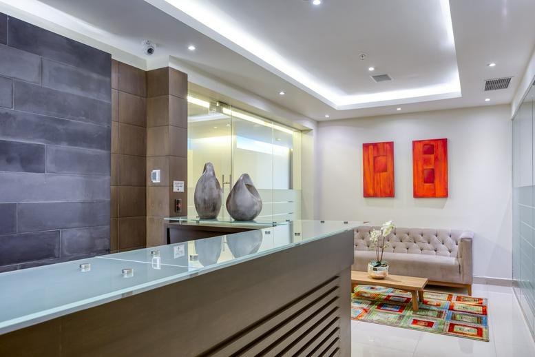 Modern lobby at Av. Jesús del Monte No. 41, piso 14 with a sleek reception desk and red wall art.