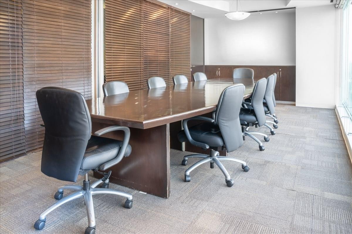 Spacious boardroom at Av. Patriotismo no 229 with a large polished wood table and black chairs.