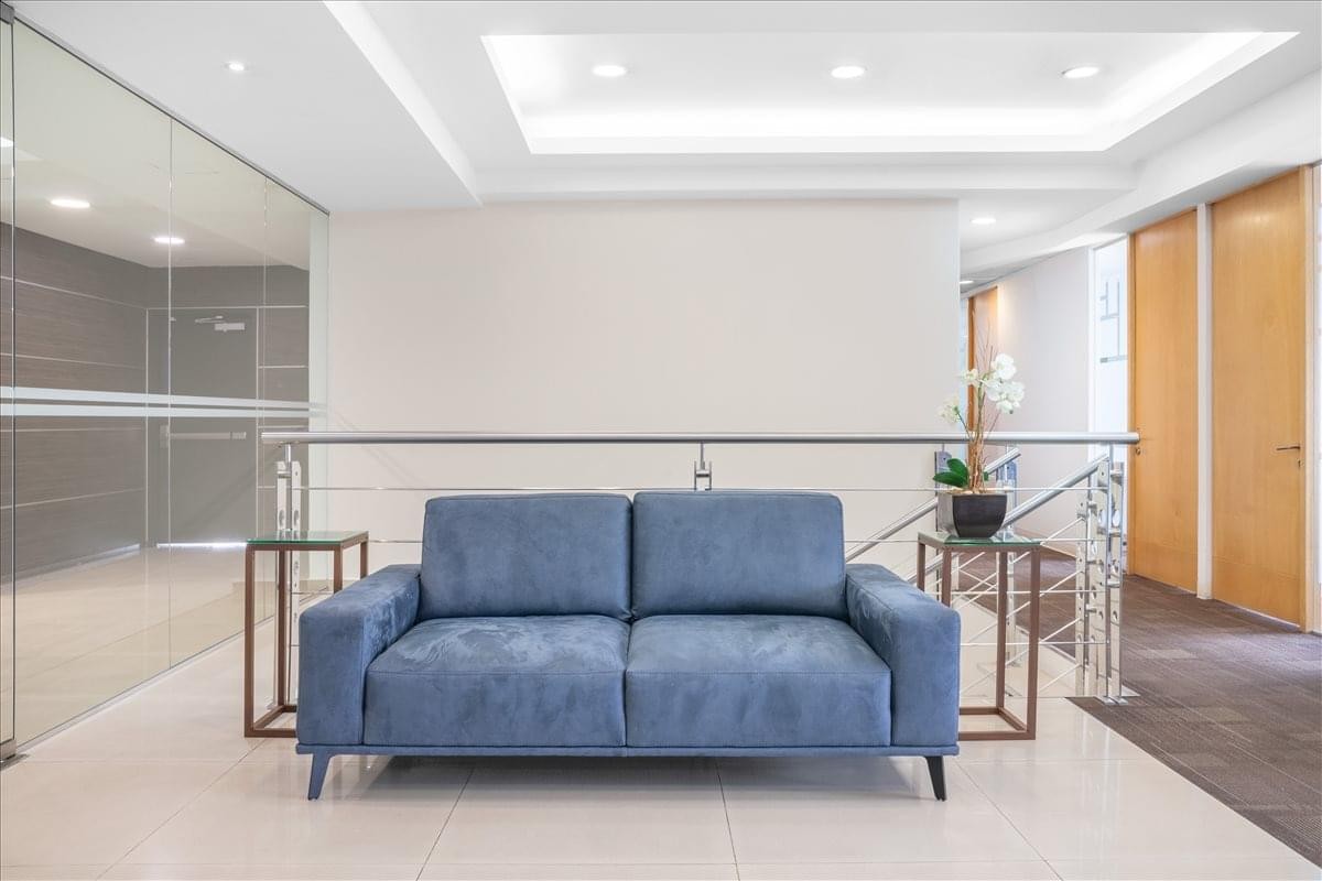 Lounge area at Av. Patriotismo 229, Floors 7 & 8, with a blue sofa and glass partitions.