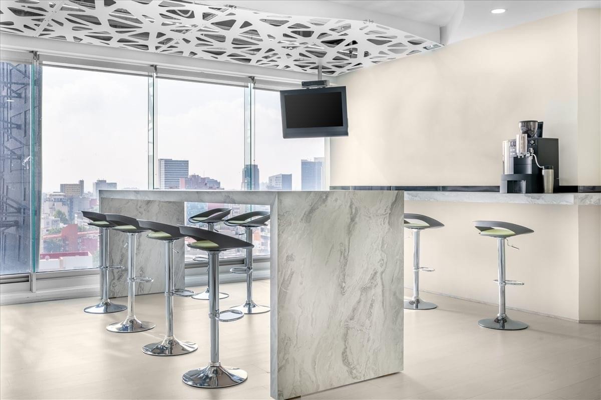 Av. Patriotismo 229 office breakroom featuring a marble-style island and high stools with city views.