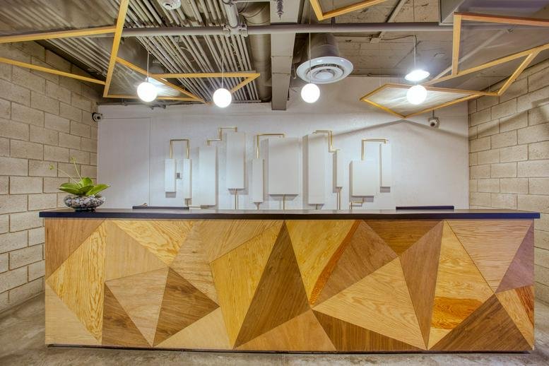 Branded reception area at Av. Rodolfo Gaona No. 3 with a geometric wood-paneled desk.