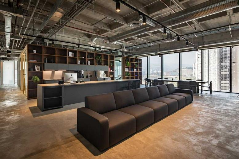 Spacious communal lounge at Torre III, Piso 15, Av. Santa Fe 428 with a long dark sofa and wooden shelving.