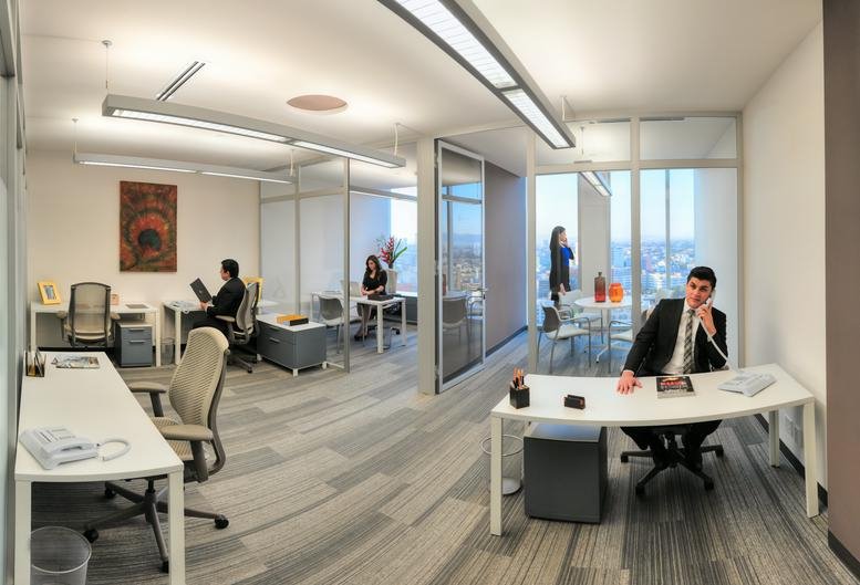 Bright open-plan office with white desks and glass partitions.
