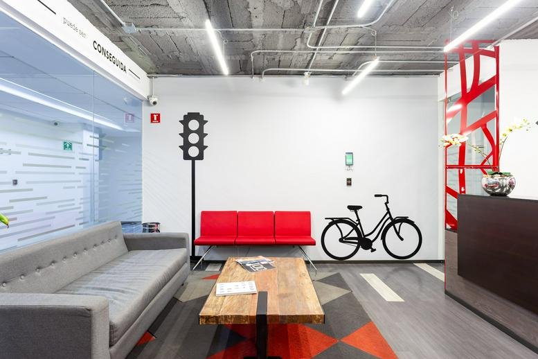 Modern lobby at Avenida Jaime Balmes 11, Torre B with a red sofa, bicycle art, and exposed concrete ceiling.
