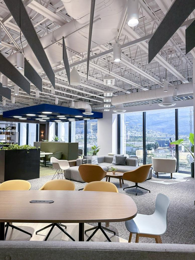 Open coworking space with yellow lounge chairs and industrial ceiling.
