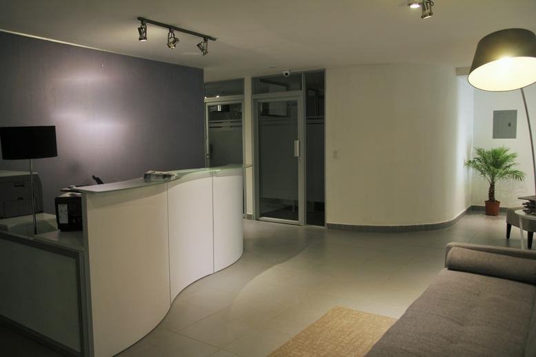 Spacious reception area with curved white desk and warm lighting at Edificio Business Point.