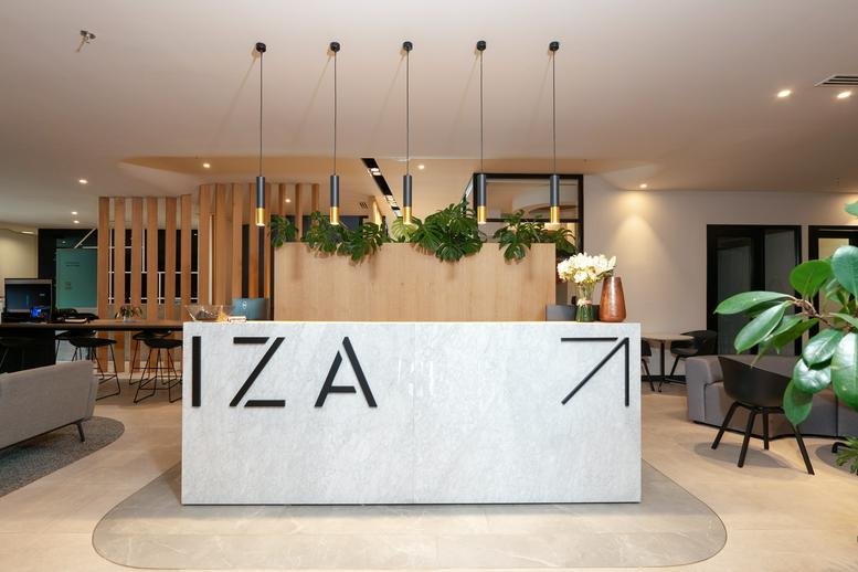 Modern white reception desk with the IZA logo under five hanging pendant lights.