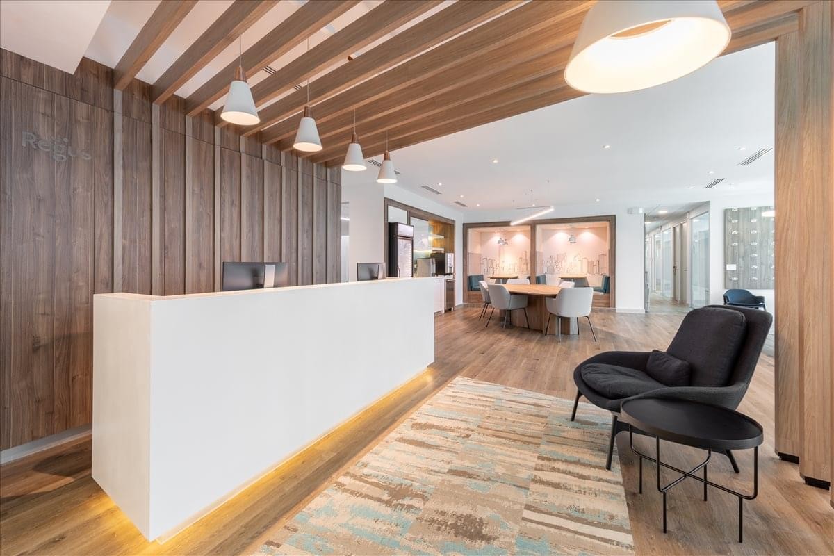 Sleek white reception desk with warm wood-paneled walls and designer lighting.