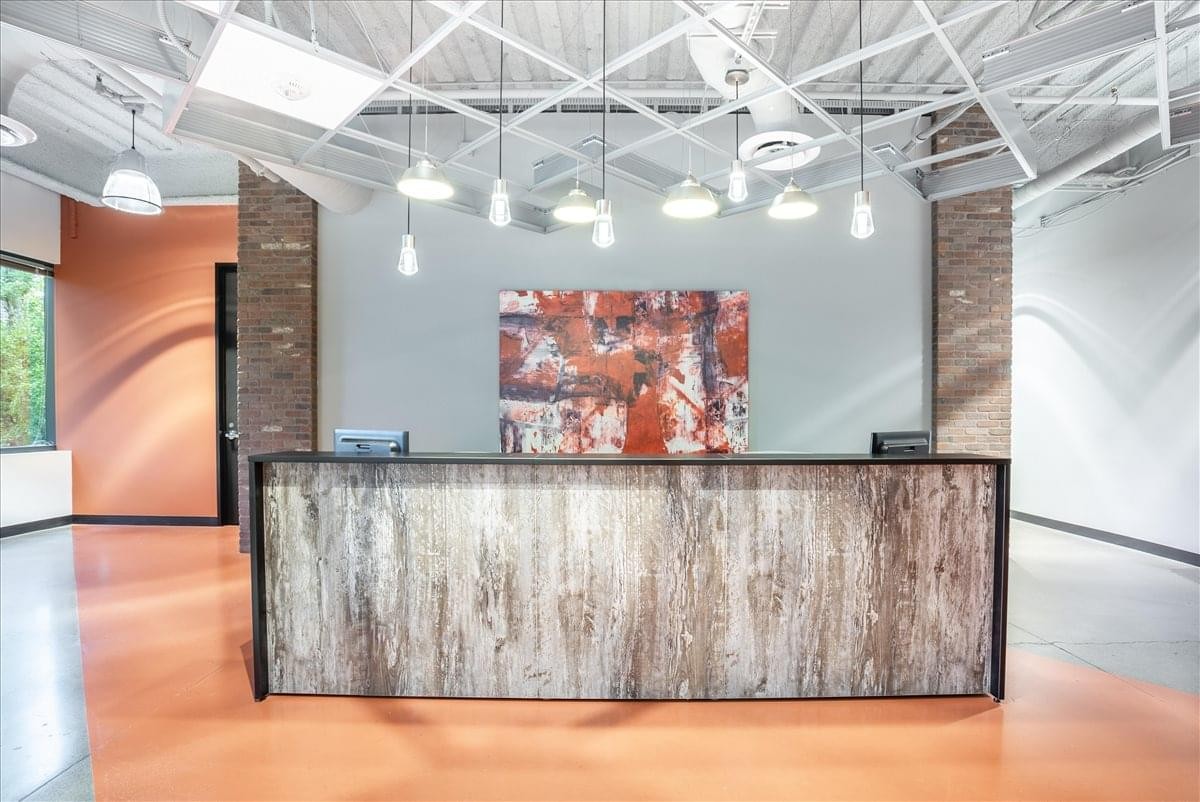 Professional reception area of Bernal Corporate Park featuring a wood-textured desk and designer pendant lighting.