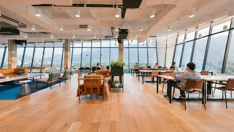 Spacious open-plan workspace with wooden floors and large windows.