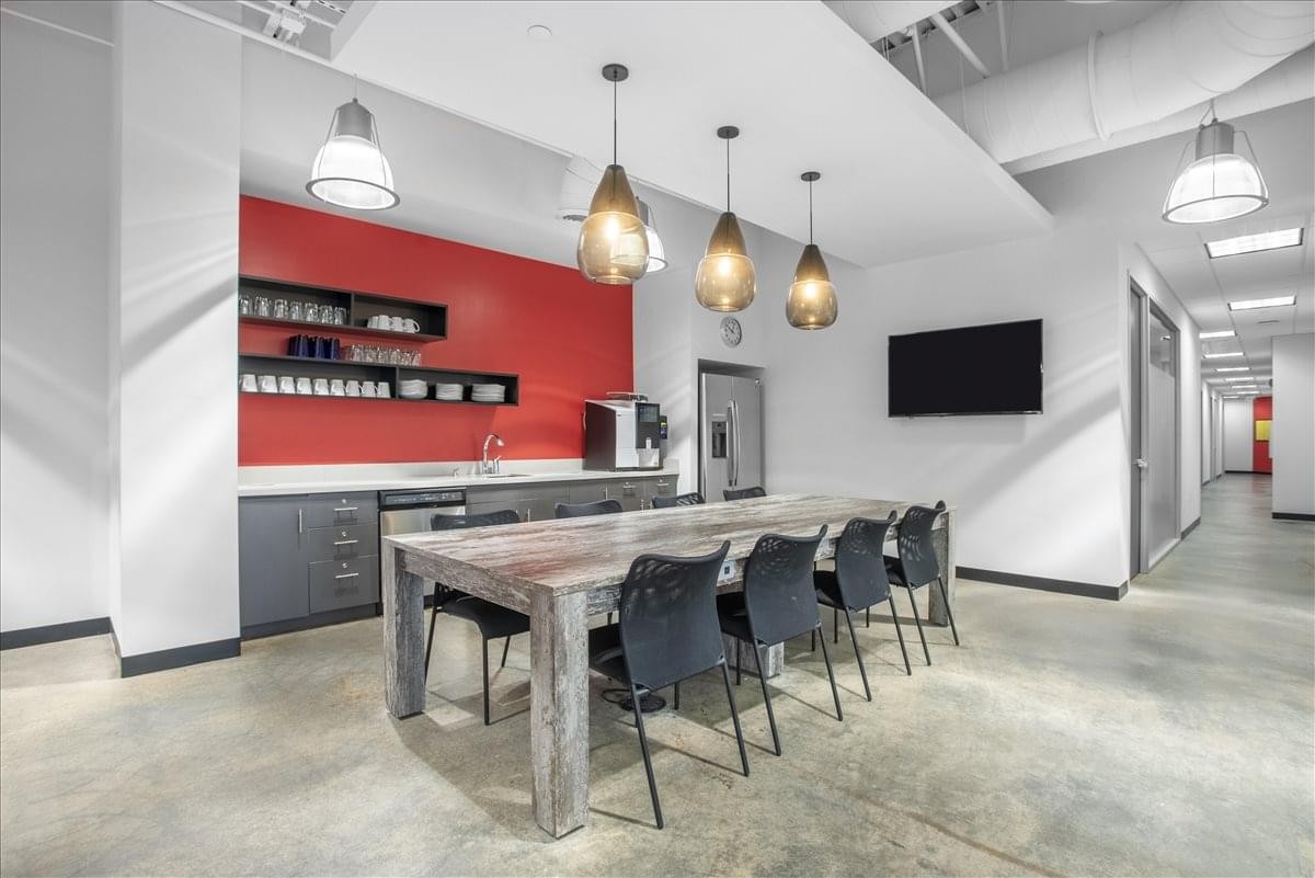 Modern breakroom at Brownsboro Crossing featuring a red feature wall, dining table, and pendant lighting.
