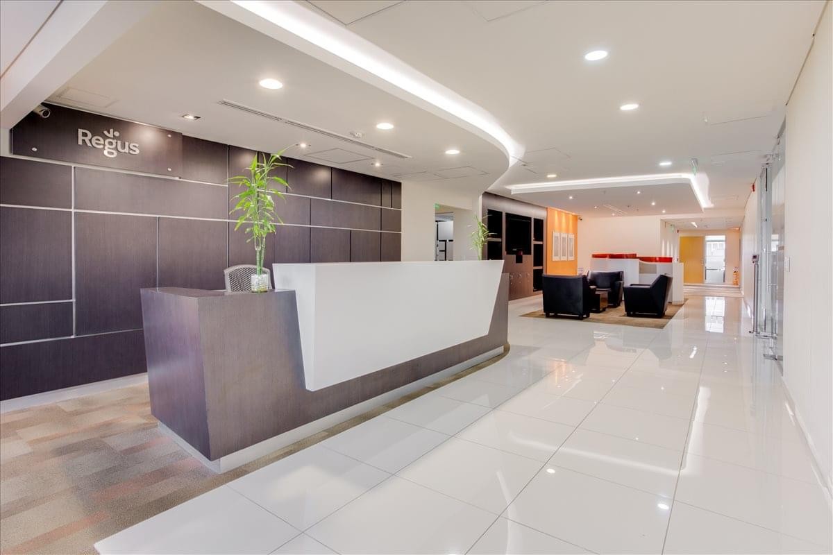 Bright, modern reception area at Building QBO Parque 93 with white desk and curved lighting.