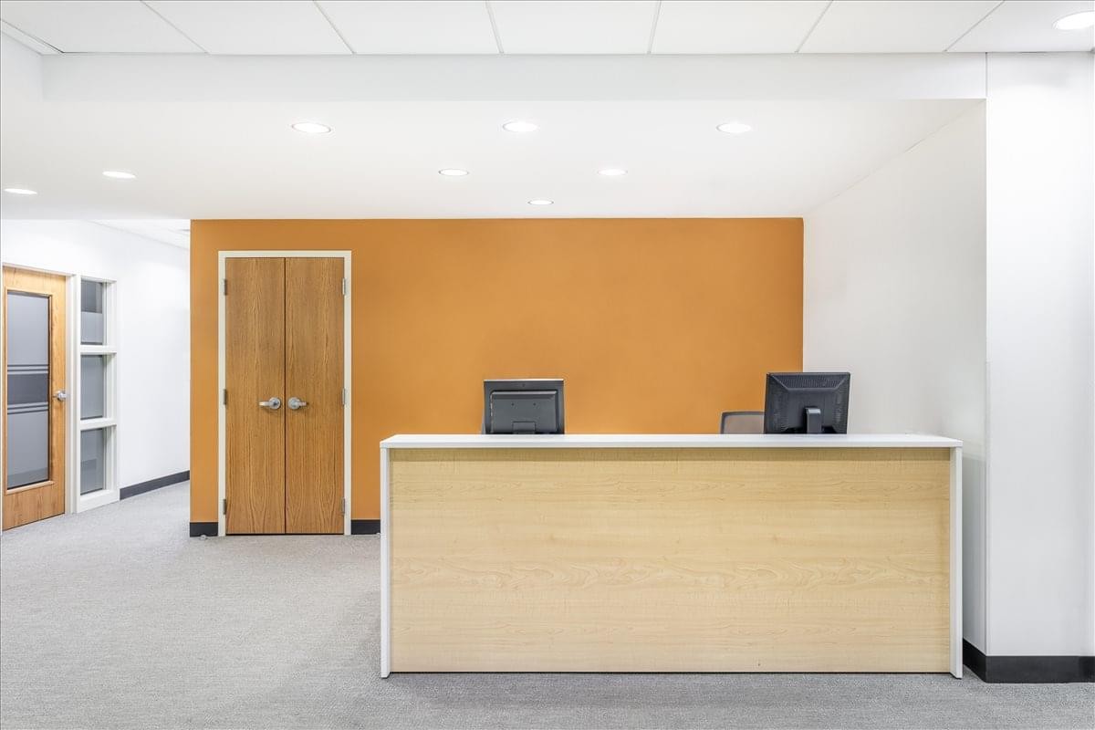 Reception area at Calder Plaza, Downtown Grand Rapids with a wooden desk and orange accent wall.