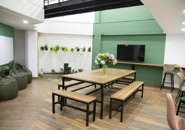 Communal breakout area at 65 D 02 Calle 34 B with wooden dining table and bean bag chairs.