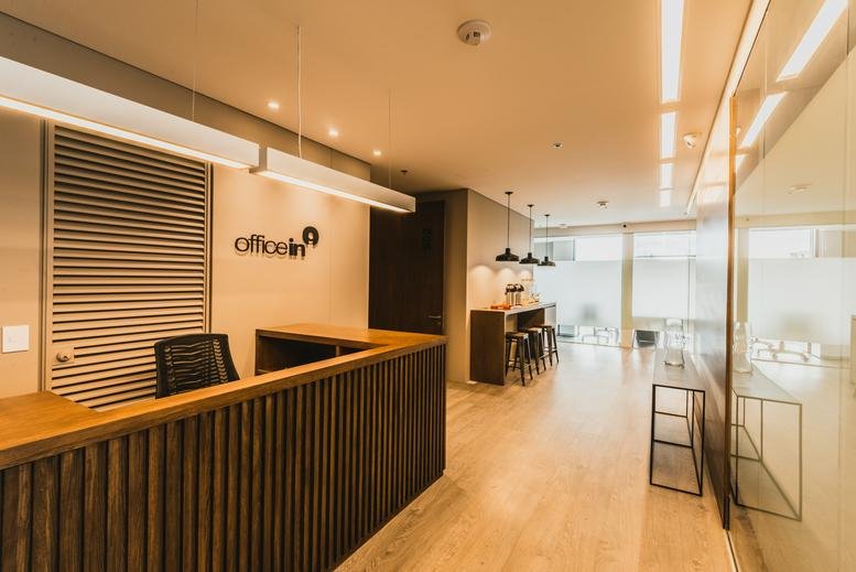 Warm, wooden reception desk at Calle 95 No 14-45 Piso 5 with brand signage and bright hallway.