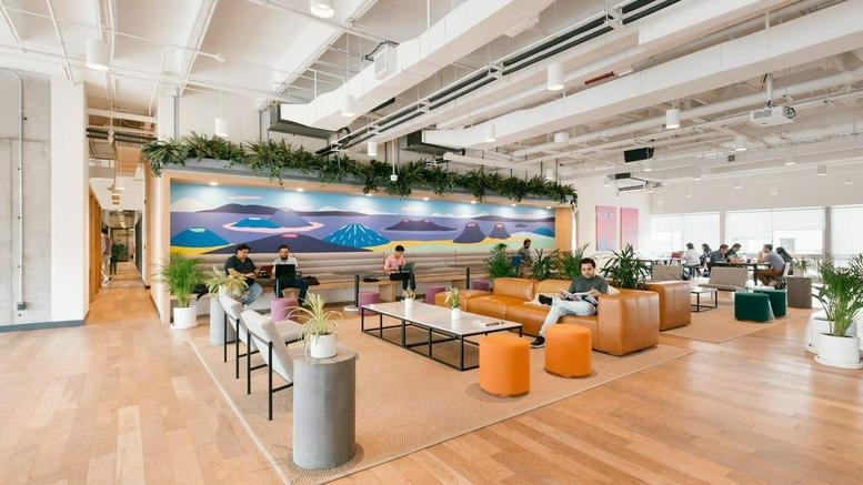 Spacious communal lounge at Calle Washington 1400 with a large colorful mural, wooden floors, and indoor plants.