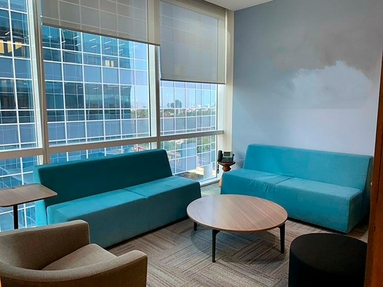 Casual breakout space with two bright turquoise sofas and a round wooden coffee table.