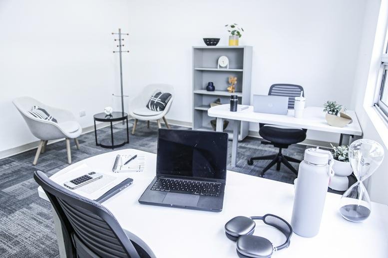 Private office setup with white desks, black chairs, and natural light from a side window.