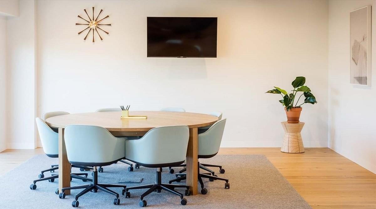 Spacious meeting room at Carrera 11 No. 79, 80 with a round wood table and light blue chairs.