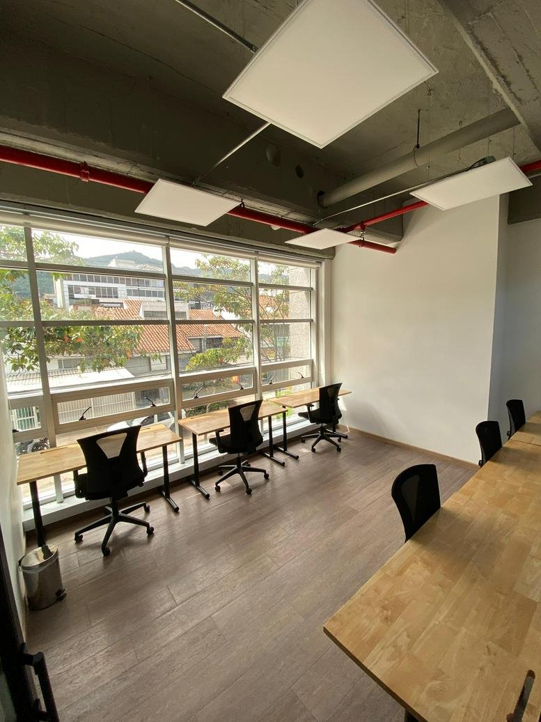 Bright open-plan workspace at Workzone, Carrera 13A No. 98-75, with light wood desks and large windows.