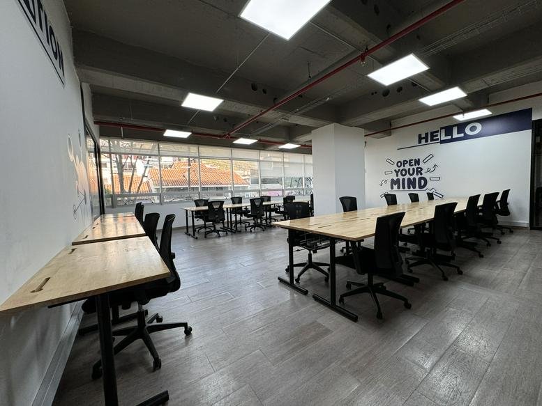 Spacious communal coworking area with multiple long tables and inspirational wall graphics.