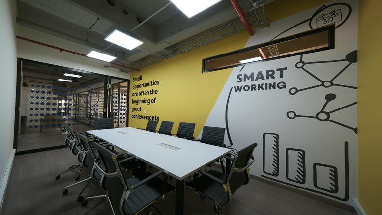 Professional meeting room at Workzone, Carrera 13A No. 98-75 featuring a 'Smart Working' mural.
