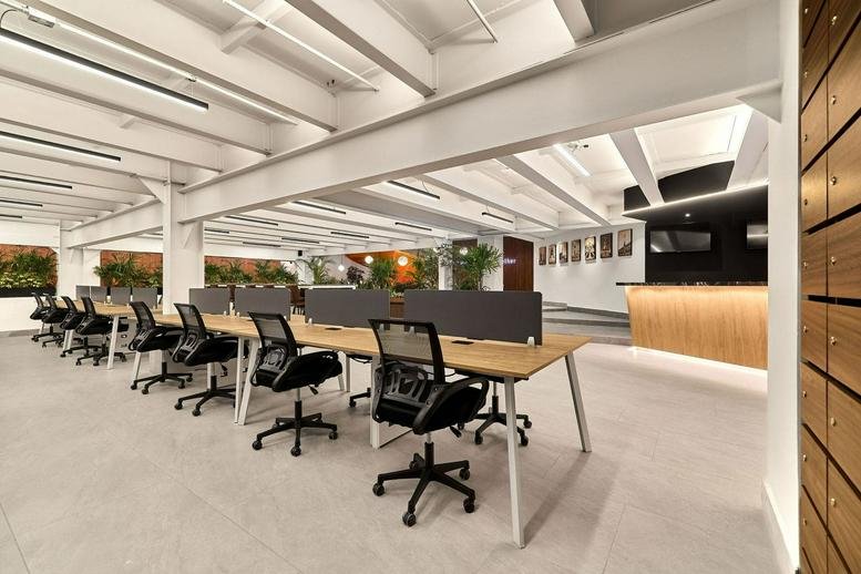 Spacious open-plan workspace at Gruta 19 CORP with modern desks and exposed white ceiling beams.