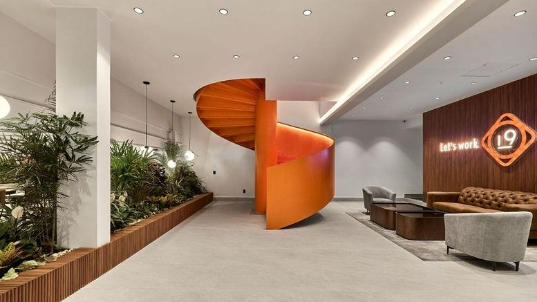 Lobby area at Gruta 19 CORP featuring a striking orange spiral staircase and indoor plants.