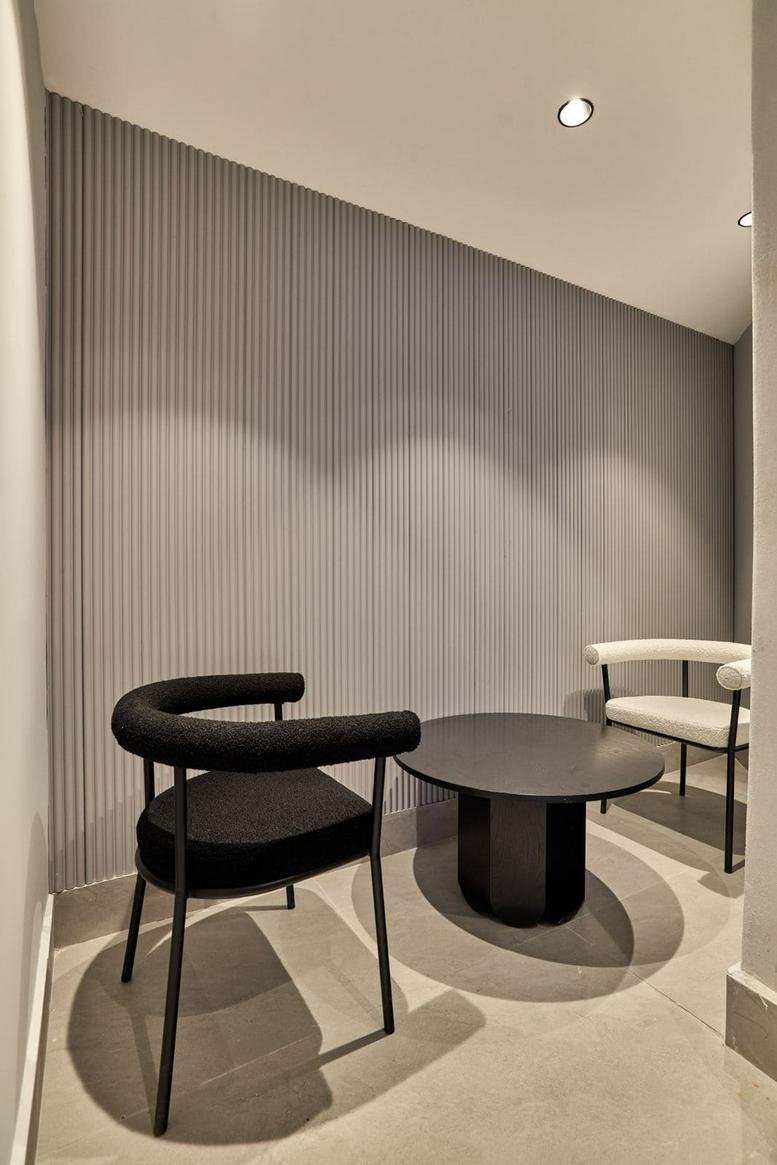 Small private meeting nook with textured grey walls and a minimalist black round table.