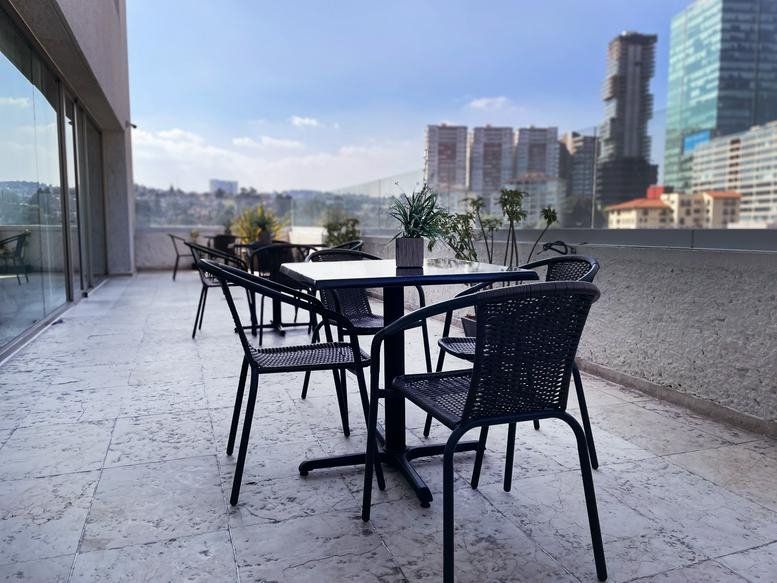 Spacious outdoor terrace at Corporativo Diamante with modern cafe seating and panoramic city views.
