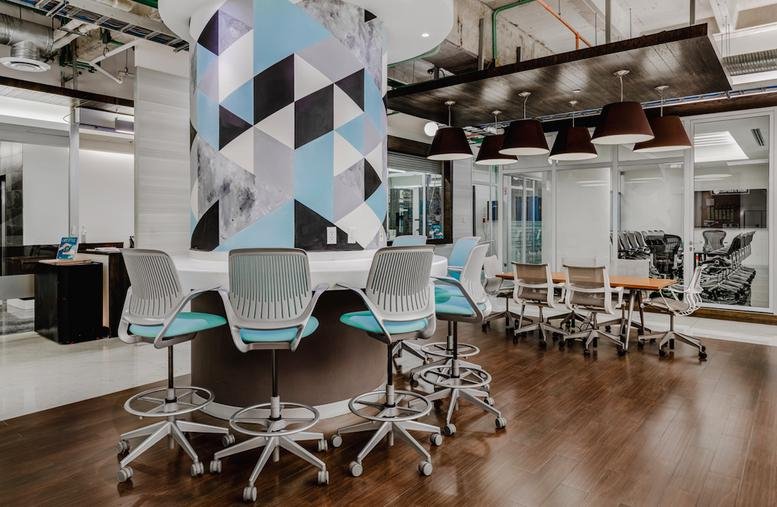 Modern breakout area with a blue geometric feature column and tall stools.
